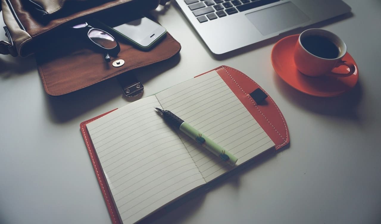 Freelancer workspace with laptop, notebook, and coffee